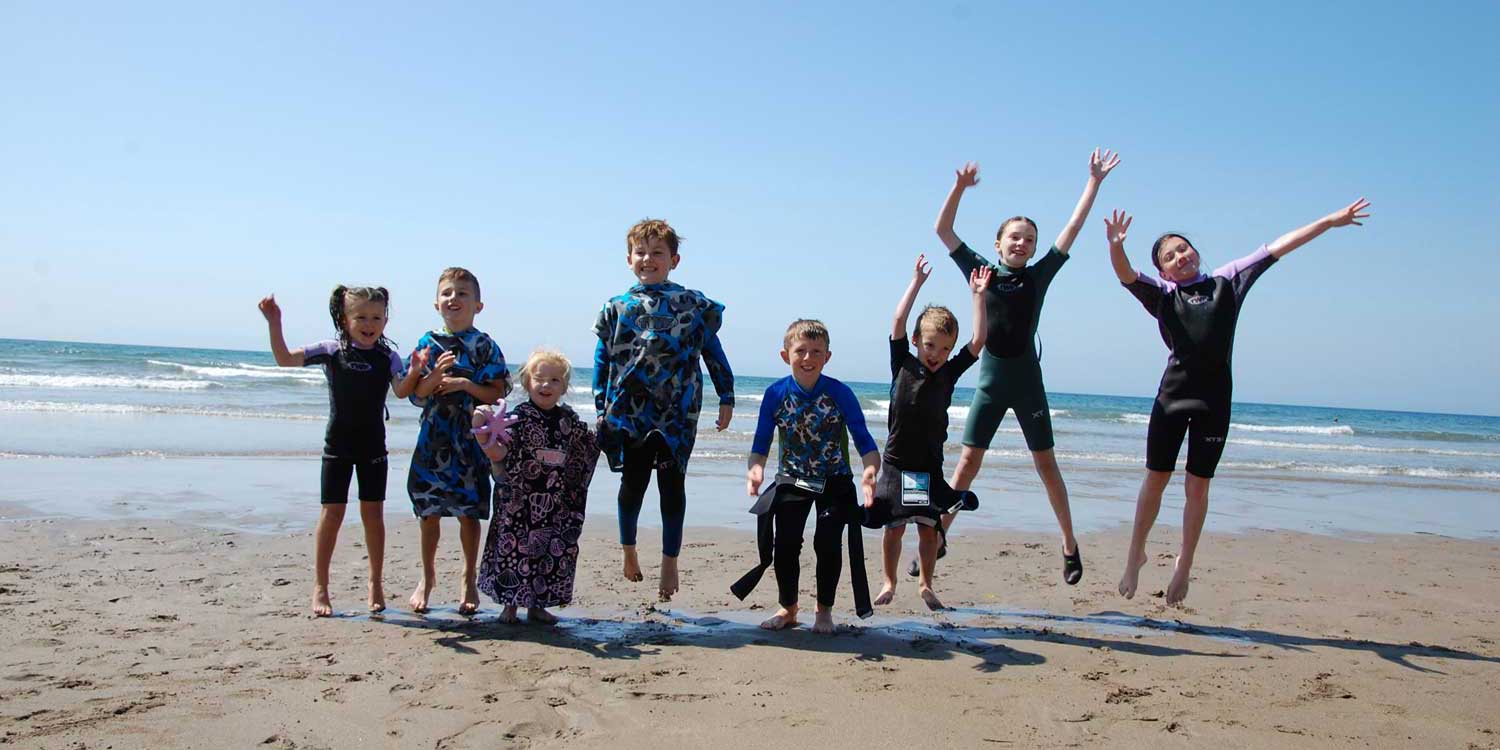 Children in wetsuits on a beach